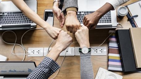 colleghi di lavoro si danno il pugno sopra la scrivania (foto: rawpixel per freepik.com)